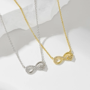 Halsketten mit Unendlichkeitssymbol und Herz in Gold und Silber auf Marmorstein