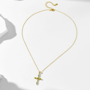 Detail of S925 silver gold cross pendant with colorful zircon and green gemstones
