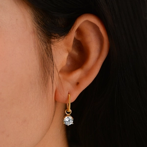 Gold twist rope hoop earrings with hanging round cubic zirconia stone on ear