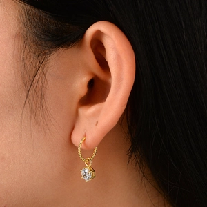 Elegant gold twisted hoop earrings with a round zircon pendant shown on ear