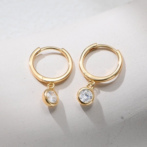 Detailed shot of gold hoop earrings featuring a single round cubic zirconia drop pendant