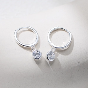 Macro detail of 925 sterling silver drop earrings featuring a bezel-set cubic zirconia