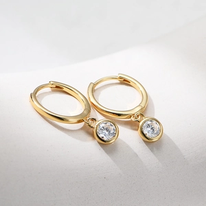 Macro shot of 925 sterling silver gold plated hoop earrings with single zircon drop