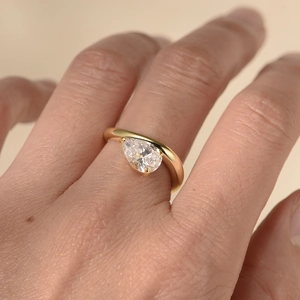 Macro side view of a gold teardrop zircon ring set on a model with a sleek band