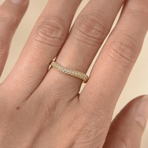 Close-up of wavy gold ring with pavé-set round cubic zirconia on a female finger