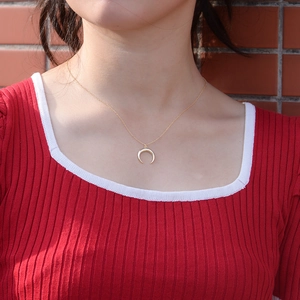 Collier avec pendentif demi-lune doré minimaliste porté par un mannequin sur un pull