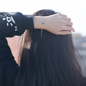 Gros plan d'un bracelet œil protecteur plaqué or 14K porté au poignet avec détail émaillé