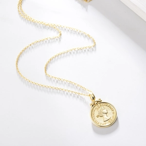 Macro shot of gold Elizabeth II coin pendant with embossed details on a fine link chain