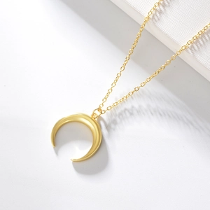 Vue détaillée d'un pendentif lune doré poli avec une chaîne minimaliste chic