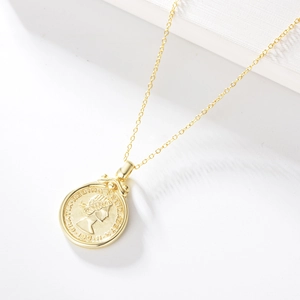 Close-up of gold Elizabeth II coin pendant necklace with embossed vintage details
