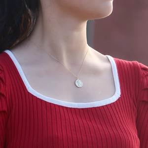 Collier médaille reine vintage en argent S925 porté sur un vêtement en tricot rouge
