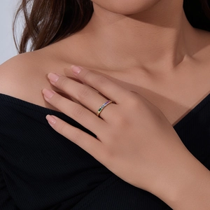 Close-up of a hand wearing a gold band with pavé set rainbow gradient zircon stones
