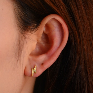 Detail shot of lightning bolt earring with pavé zircon stones on a female model