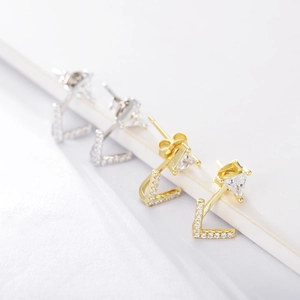 Macro detail of geometric triangle arrow earrings in silver and gold with pavé zircon