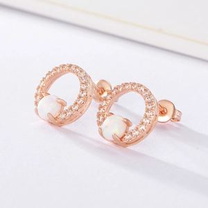 Dettaglio macro di orecchini a cerchio in oro rosa con opale bianco e zirconi