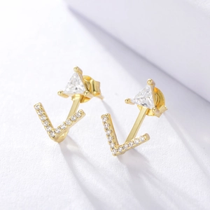 Macro detail of gold-plated geometric triangle earrings with pave zircon V-shaped accents