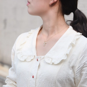 Gros plan d'un collier doré BABE avec cristaux porté au cou d'une femme