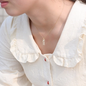 Gros plan sur collier S925 doré avec pendentif BABE et détail de cœur sur modèle