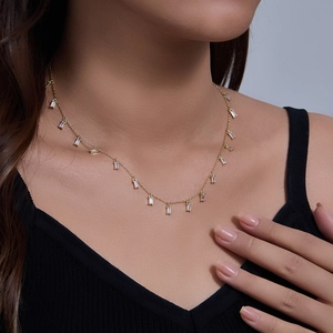 Detail of s925 silver gold-plated choker with dangling rectangular zircon stones on collarbone