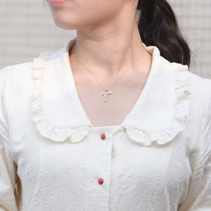 Collier doré avec lettres BABE, éclair et zircon porté sur un col en dentelle