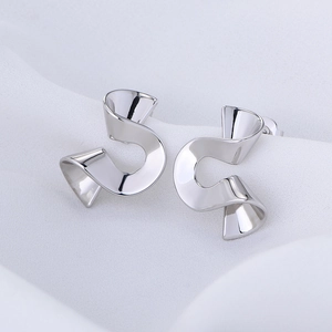 Close-up of elegant silver spiral earrings with a polished finish on white silk