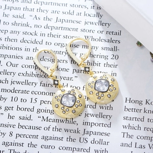 Detail of vintage square zircon earrings with 14K gold matte finish on magazine background