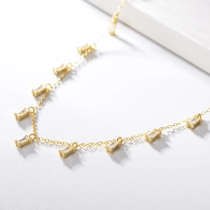 Detailed close-up of a gold necklace with sparkling rectangular zircon fringe pendants