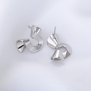Irregular spiral silver earrings with a vintage geometric twisted design on fabric