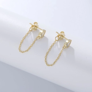 Elegant gold drop earrings with pear-cut zircon and U-shaped chain on white pedestal