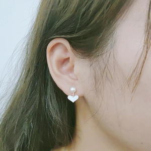Close-up of S925 silver heart stud earring with pearl detail shown on model ear