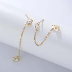 Macro detail of gold S925 silver earrings with drop-shaped zircon and chain link design