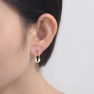 Detail of minimalist gold U-shaped paperclip earrings with white enamel inlay for women