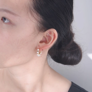 Gros plan de créoles élégantes en or avec de petites perles blanches sur un mannequin