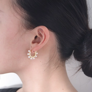 Élégantes créoles dorées avec perles blanches pour femme en vue sur mannequin