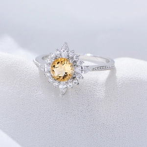 S925 Silberring mit Citrin und Blumen-Halo-Effekt auf weißem Stoffhintergrund