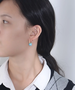 Close-up of gold coffee bean earrings with blue enamel and pavé zircon on model