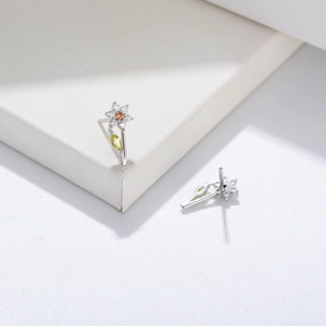 Detailed macro of flower stud earring with orange gem center and green leaf zircon