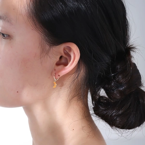 Nahaufnahme eines Models mit gelben mondförmigen Silberohrringen und kleinen Zirkonia