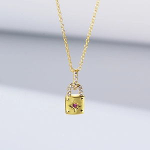 Détail d'un collier cadenas en or avec pierre rouge gravée d'une étoile et pavé de diamants