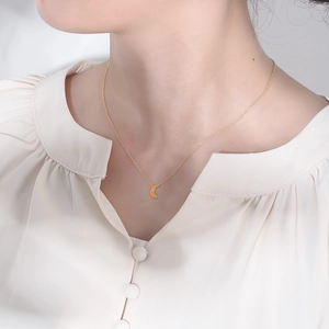 Detail of s925 silver moon pendant with orange enamel and zircon on neck