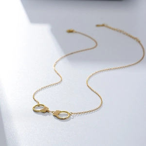 Collier menottes en argent S925 doré avec zircons blancs sur un fond gris épuré