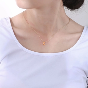 Close-up of gold S925 sterling silver chain with orange enamel moon pendant on a model