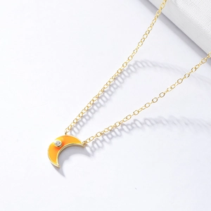 Detailed shot of golden crescent moon pendant with orange gradient enamel and zircon