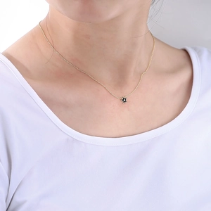 Gros plan d'un collier ras du cou doré avec pendentif étoile noire en émail poli