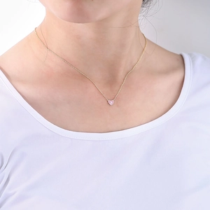 Gros plan d'un pendentif cœur rose avec un petit zircon sur une chaîne dorée en argent