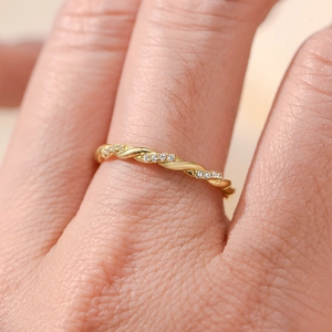 Macro detail of gold twisted rope ring with sparkling pave diamonds worn on finger