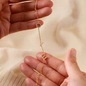 Close-up of golden LOVE letter bracelet with micro-pave white cubic zirconia stones