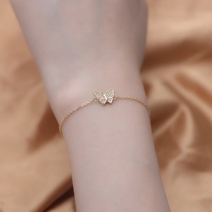 S925 sterling silver gold butterfly bracelet with white zircon worn on wrist with silk background