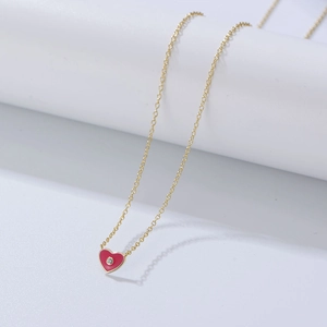 Gros plan du pendentif cœur rouge avec un petit diamant sur une chaîne dorée fine