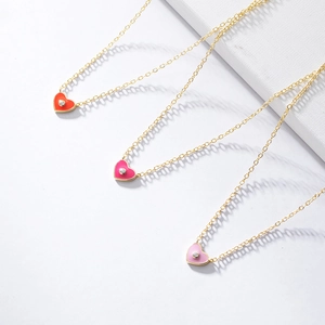 Détail de pendentifs cœur en émail coloré avec petits diamants sur des chaînes dorées